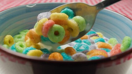Close-up hands of a lonely man eating colorful cereal for breakfast, lack of appetite. delicious and nutritious fruit flakes.Man eats round colorful cereal with milk for breakfast close-up - Powered by Adobe