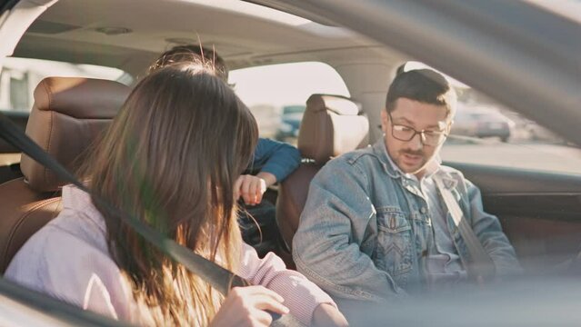 Preparation before family car trip. Happy lovely family fastening safety belts smiling looking forward to journey. Beautiful woman sitting with handsome man and cute kids in automobile.