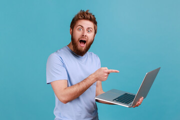 Man pointing finger at laptop with opened mouth and big eyes, expressing astonishment.