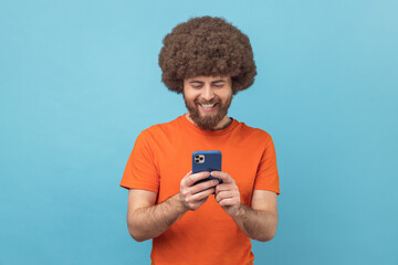 Man blogger standing, using smartphone and watching video with happy smiling face.