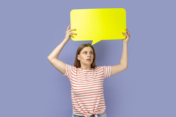 Woman looking away and holding yellow bubble thought over her head, copy space for text.
