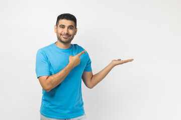 Joyful smiling happy unshaven man presenting advertisement area on his palm, mockup.