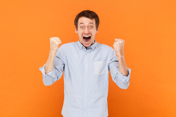 Extremely happy man standing with clenched fists, celebrating his success, screaming hurray.
