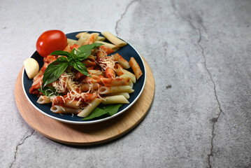 pasta in tomato sauce with basil leaf on a plate on a wooden tray