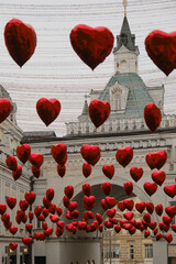 Decorations in Moscow for Valentine's Day. Garlands in the form of red balls in the shape of a heart hang between historical buildings of architecture in daylight.