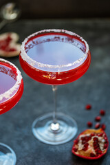 Two glasses with red pomegranate cocktail. Party, mixed colourful cocktail. Dark background, creative soft focus.