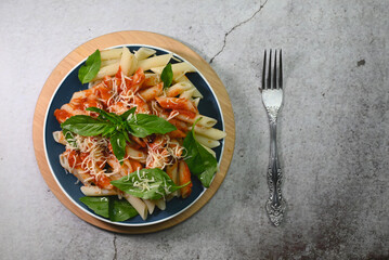 pasta in tomato sauce with basil leaf on a plate on a wooden tray