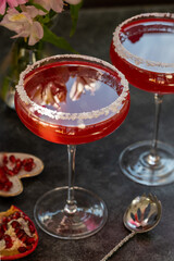 Two glasses with red pomegranate cocktail. Party, mixed colourful cocktail. Dark background, creative soft focus.