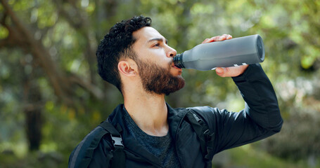 Man drinking water hiking in a forest, nature or woods outdoors in jungle adventure with freedom in...