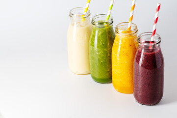 Fresh fruit smoothies bottles with straws. Healthy detox drinks, bright background