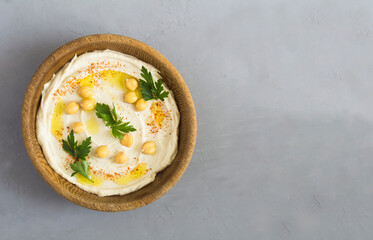 Hummus in the brown bowl on the gray cement background. Top view. Copy space.
