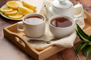 Two cups of black tea, tea pot and lemon slices. Tea time.