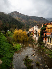 Fototapeta na wymiar imagen de un pequeño pueblo de montaña con el río cruzándolo y el cielo nublado 