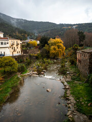 Fototapeta na wymiar imagen de un pueblo de de montañas con el río que lo cruza y casas a ambos lados y el cielo nublado 