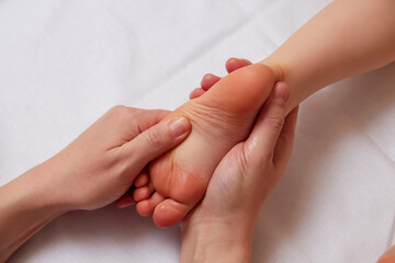 Doctor performing pediatric foot massage to prevent development of flat feet - 573996420