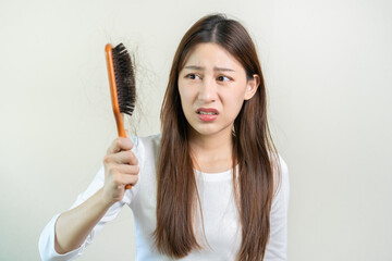 Serious, worried asian young woman, girl holding brush, show her comb, hairbrush with long loss...