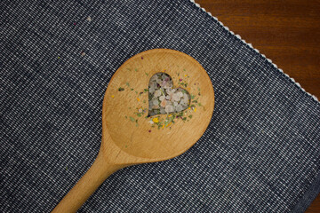 wooden spoon with a heart cutout on a blue and white doily and the heart is filled with colourful...