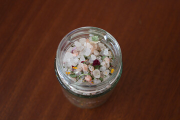 glass container, jar with salt and herbs on a dark wood table, close up, macro