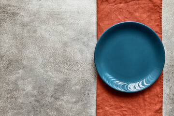 Empty blue ceramic plate on terracotta linen napkin, with copy space - 573997801