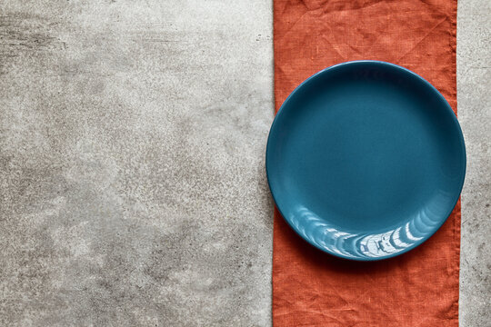 Empty blue ceramic plate on terracotta linen napkin, with copy space