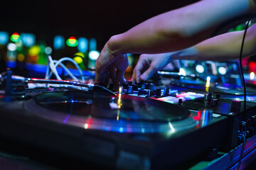 Hip hop DJ mixing music with vinyl records and sound mixer. Hands of disc jockey playing set on party in night club.