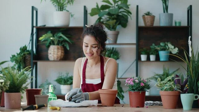 Video of influencer woman arranging plants and flowers while recording a tutorial video with smartphone in a greenhouse