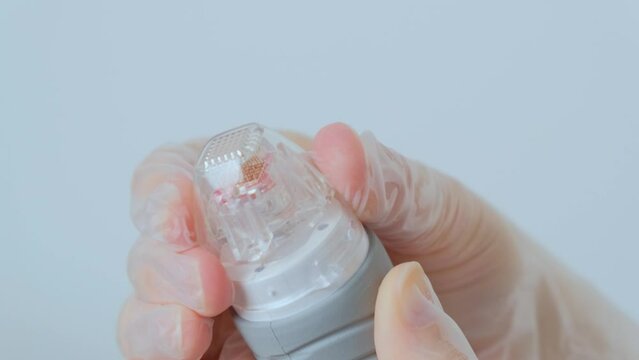 The hands of a cosmetologist dress the nozzle for the cosmological procedure. The needle rf-figure. Room, white background. Cosmetology and medical services. The device for lifting radio frequency rad