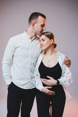 Young couple in love in white shirts hugging on a white background. A happy married couple looks lovingly into each other's eyes. The concept of healthy family relationships