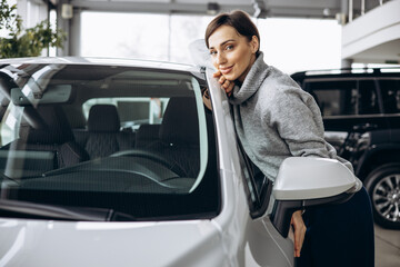 Beautiful woman choosing a car in a car showroom