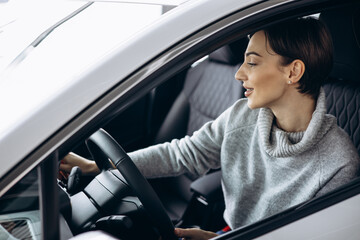 Young woman sitting in car in a car showroom