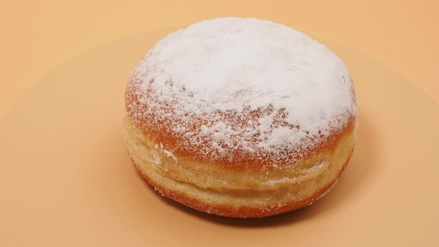 Freshly baked and powdered German donuts. Berlin donut or krapfen on orange background.