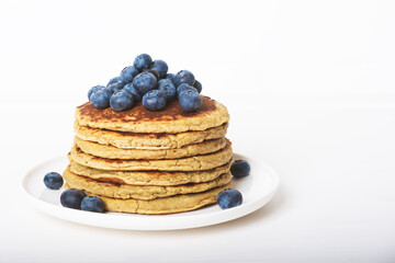 Delicious freshly cooked avocado pancakes stacked on white plate served with fresh blueberries. Copy space for text. Healthy gluten free food.