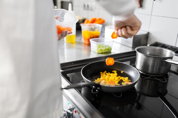 cooking food, profession and people concept - close up of male chef with frying pan stewing vegetables at restaurant kitchen