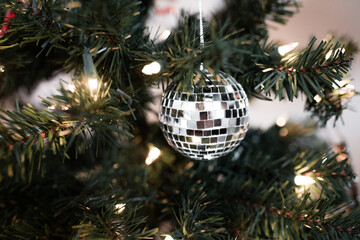 A festive indoor holiday celebration is set inside the branches of a Christmas tree. A disco ball...