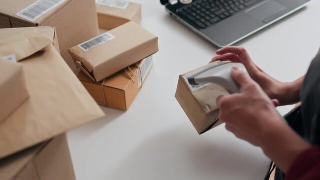Cardboard boxes, Courier service entrepreneur Responsibly scans a barcode at packer's workplace, Close-up The packer of goods is in the factory of progressive technologies of the future, storage.
