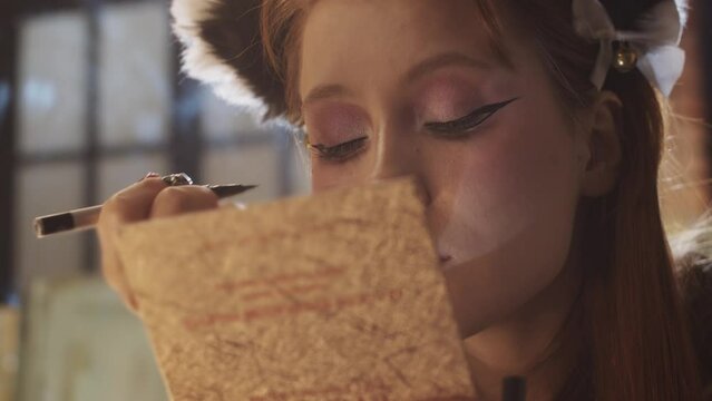 A cute girl doing makeup - drawing dramatic winged eyeliner looking in a small mirror