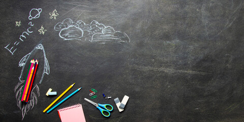 Back to school concept. School supplies on black board background.