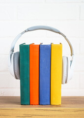 Fototapeta na wymiar Audio books concept. Wireless Headphones and color books at table.