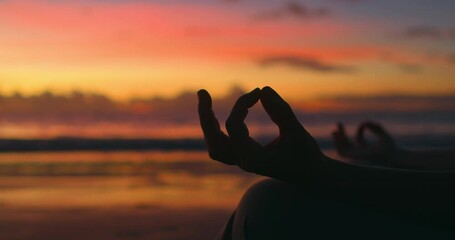 Woman does yoga at dawn on ocean. Silhouette of woman's hands. Meditation, practice of zazen in Buddhism. Calming body, contemplating, enlightenment. Gesture of index and thumb connected in ring.