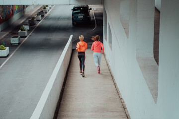 Two women in sports clothes running in a modern urban environment. The concept of a sporty and healthy lifestyle