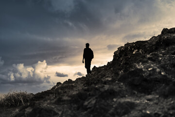silhouette of a person on a mountain top looking out into the distance 