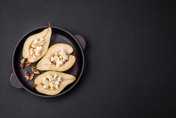 Delicious baked pear with dorblu cheese, walnut and honey on a textured concrete background
