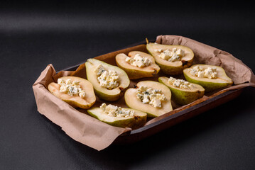 Delicious baked pear with dorblu cheese, walnut and honey on a textured concrete background