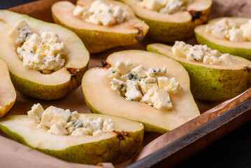 Delicious baked pear with dorblu cheese, walnut and honey on a textured concrete background