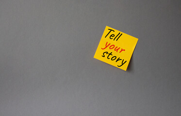 Tell your story symbol. Concept words Tell your story on orange steaky note. Beautiful grey background. Business and Tell your story concept. Copy space.
