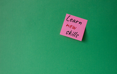 Learn new skills symbol. Concept words Learn new skills on pink steaky note. Beautiful green...