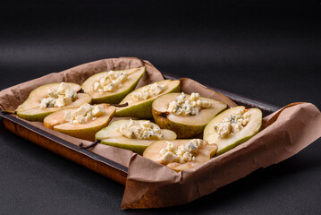 Delicious baked pear with dorblu cheese, walnut and honey on a textured concrete background