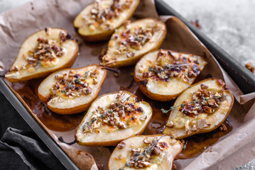 Delicious baked pear with dorblu cheese, walnut and honey on a textured concrete background