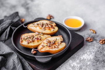 Delicious baked pear with dorblu cheese, walnut and honey on a textured concrete background