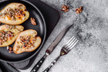 Delicious baked pear with dorblu cheese, walnut and honey on a textured concrete background